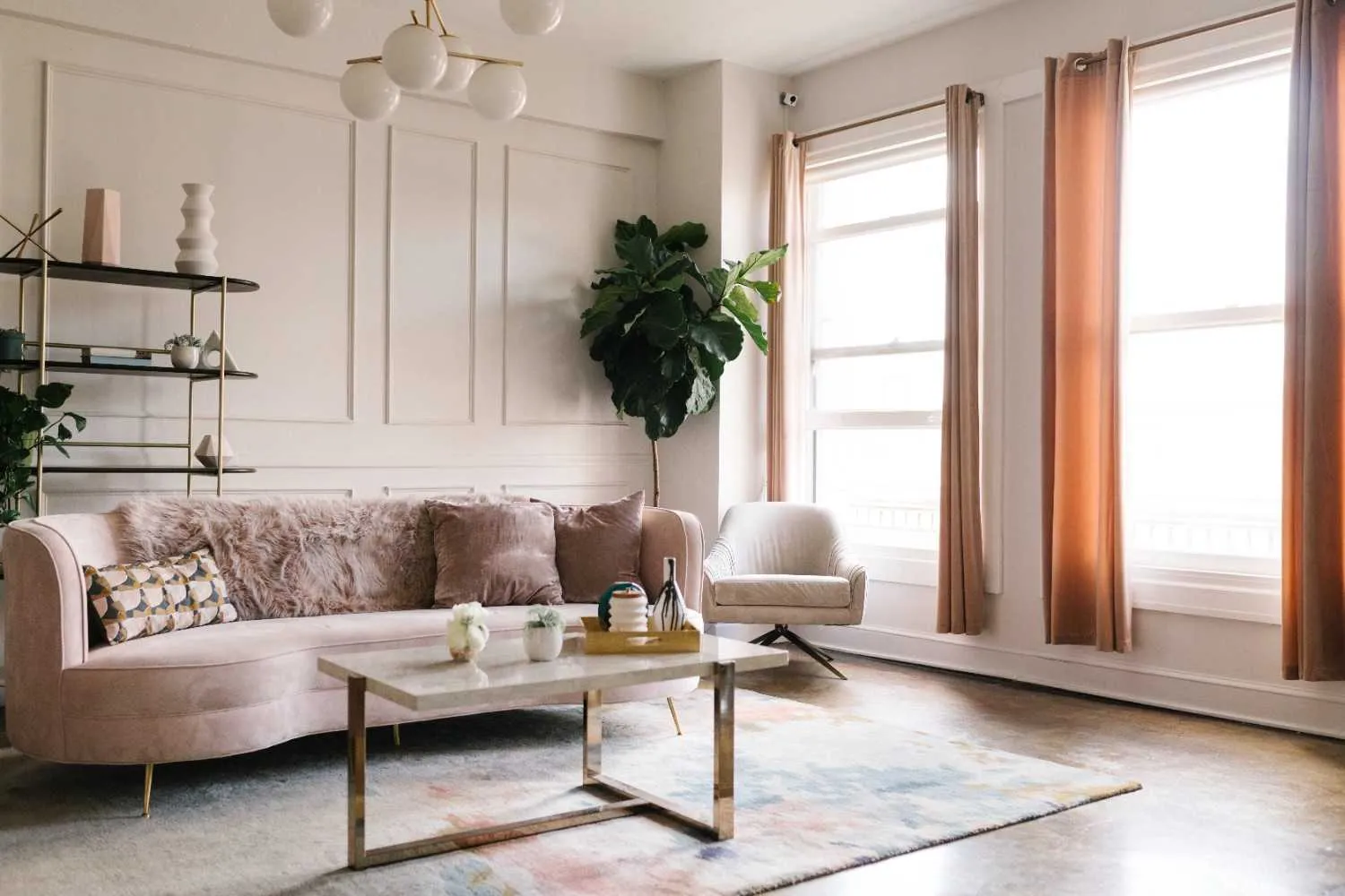 Bright living room with a pink sofa, coffee table and tall windows